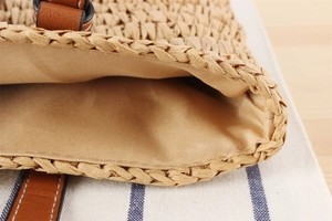 Close-up of woven straw tote bag with premium leather trim and soft inner lining details