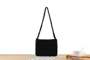 Detail shot of black hand-woven cotton rope shoulder bag on a light wooden table