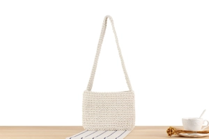 Close-up of cream white hand-knit shoulder bag with detailed wavy crochet texture and strap