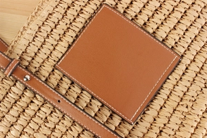Detailed close-up of handmade woven straw texture with caramel leather trim and stitching