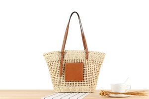 Détail du sac fourre-tout en paille tissée avec patch et anses en cuir marron