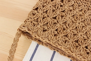Macro detail of hand-woven straw bag showing 3D floral pattern and zipper closure