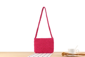 Detailed close-up of vibrant pink woven cotton rope shoulder bag on a rustic table