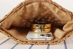 Macro view of woven straw bag interior showing storage space for phone and makeup