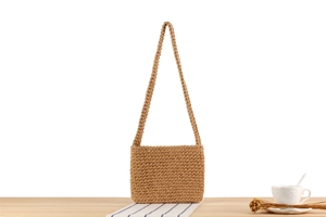 Detail of handmade khaki woven cotton shoulder bag on a stylish wooden table setup