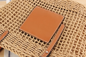 Détail du sac en paille avec patch en cuir marron et texture tissée artisanale