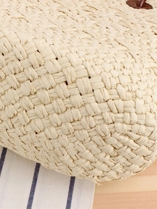 Minimalist beige woven straw tote bag with brown leather handles in a vacation style