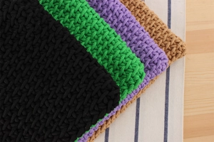 Macro texture view of thick cotton rope woven coasters in black green and purple