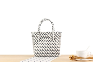 Detail of hand-woven striped storage basket with black and white chevron pattern on a table