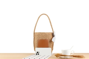 Detail der Stroh-Eimertasche mit Lederpatch, Punkt-Schleife und Größenvergleich im Bild