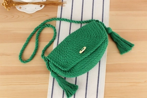 Détail du sac à bandoulière en crochet vert avec pompons et bouton en bois naturel