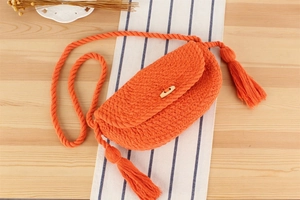 Détail du sac bandoulière orange tissé avec bouton en bois et longues franges latérales