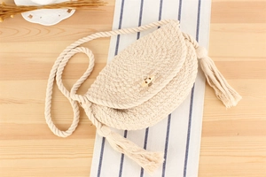 Gros plan d'un sac en coton tisse avec de longs pompons et une fermeture à bouton en bois