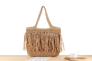 Makro-Detail der Strohtasche mit langen Fransen und gewebter Textur für den Sommerurlaub