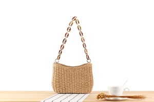 Detail of paper straw woven bag featuring vintage amber acrylic chain strap and texture