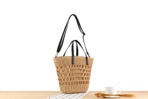 Detail of woven straw tote bag with black leather handles and detachable shoulder strap