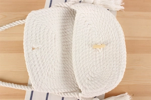 Détail d'un sac à bandoulière en coton tissé blanc avec bouton en bois et longues franges