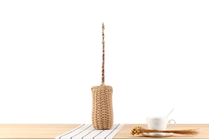 Detail of woven straw bucket bag with amber acrylic chain on a rustic wooden table
