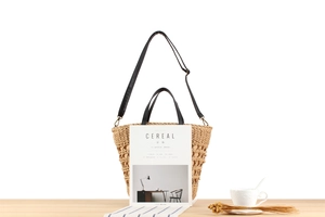 Detail of woven straw bucket bag with black leather handles and interior lining