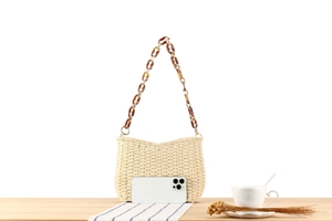 Detail of paper straw woven shoulder bag with amber acrylic chain and smartphone for size