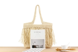 Detail der handgewebten beigen Strohtasche mit langen Fransen für den Strandurlaub
