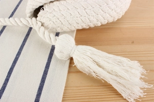 Gros plan d'un sac en coton tressé blanc avec des franges délicates sur une table en bois