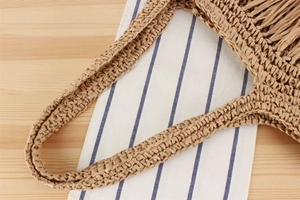 Detailaufnahme des gewebten Strohgriffs und der Textur einer beigen handgefertigten Tasche