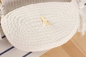 Détail d'un sac tissé en coton crème avec bouton en bois naturel et élégants pompons