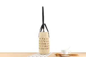 Close-up of beige hollow woven bucket bag with black handles and fine texture