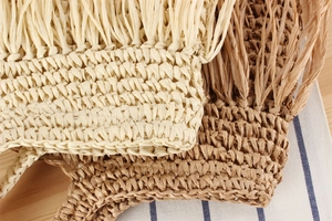 Makro-Detail der handgewebten Strohtasche mit natürlichen Texturen und langen Fransen