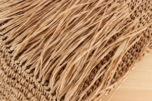 Makro-Detail der handgewebten Textur und langen gedrehten Quasten an einer beigen Tasche