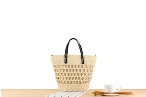 Detail of beige woven tote bag with hollow diamond mesh and black leather handles