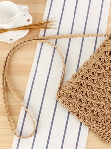 Handmade woven paper rope shoulder bag with hollow star pattern on a wooden table