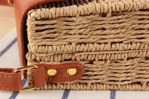 Macro shot of straw woven texture with premium brown leather trim and gold metal hardware