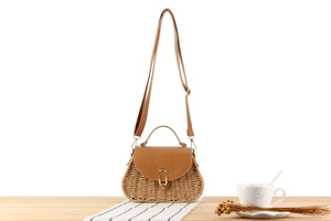 Detailansicht der Strohtasche mit brauner Lederklappe und goldenem U-förmigem Metallschloss