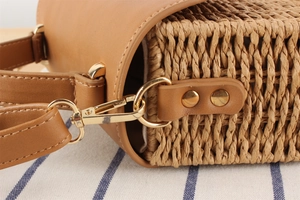 Detail der Strohtasche mit Kunstleder-Riemenverbindung und goldenen Metallbeschlägen
