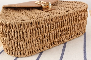 Detail der gewebten Strohtasche mit brauner Lederklappe und goldenem Metall-Verschluss