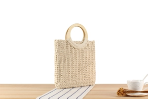 Detail of beige cotton woven handbag with round wooden handles on a rustic table setting