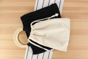 Detailed view of black woven tote with round wooden handle and canvas inner pouch