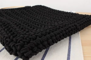 Detail of handmade black cotton rope crochet texture with rustic wooden handle accents
