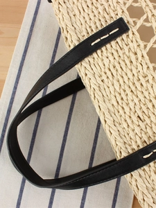 Hollow out woven beach tote with black leather straps on a nautical background