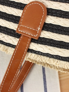 Large striped straw beach tote bag with brown leather handles and fringe detail