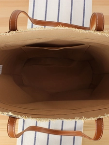 Striped woven straw tote bag with brown leather handles and a secure zipper interior