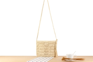 Détail du sac bandoulière en paille tissé main avec pompons et texture vague