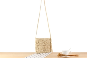 Vue détaillée du sac de plage en crochet beige avec motifs ondulés et pompons
