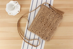 Détail du sac bandoulière en paille tissé main avec pompon et fermeture à bouton en bois