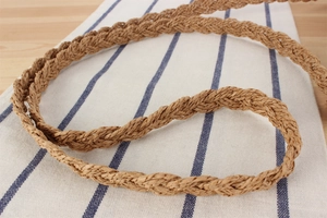 Détail de la texture d'un sac en paille tissé à la main avec franges sur lin rayé