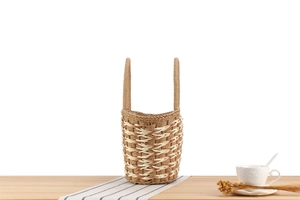 Detail of woven straw tote bag with textured wavy patterns on a rustic wooden table