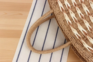 Close-up of woven straw handbag texture and dual-tone braided handle on wood background