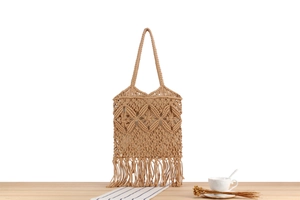 Close-up of handmade bohemian woven cotton tote bag with intricate hollow patterns and tassels